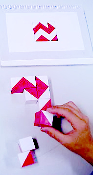 red and white blocks with a hand putting them together to match a picture