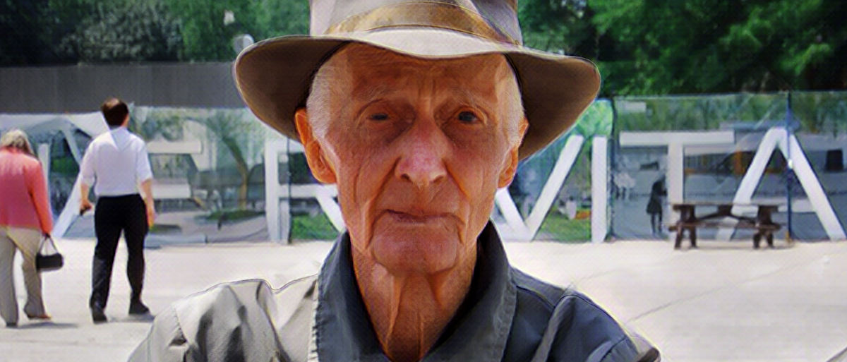 Old man staring right into the camera wearing a fedora, folded hands, worn eyes