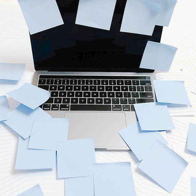 black and silver laptop with blue sticky notes